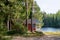 Red wooden finnish cabins cottages in green pine forest near river. Rural architecture of northern Europe