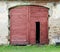 Red wooden gate of the old rustic shed