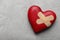 Red wooden heart with sticking plasters on light grey stone table, top view. Space for text