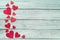 Red wooden hearts on the left border on a green wooden background