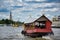 A red wooden traditional boat with tourist is crossing the Chao Phraya River towards the famous and amazing Wat Arun ancient Thai