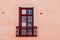 Red wooden window of a house and brick colored facade