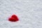 Red wool felted heart lies on the white snow. Lost heart side view