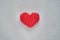 Red wool felted heart lying on white sheet