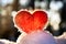 Red wool felted heart stands on the snow and backlighted by setting winter sun