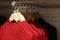 Red woolen knitted sweaters hanging on hangers in the store, close-up