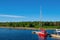 Red yacht against the blue sky and green forest.