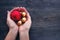 Red and yelllow round christmas balls in male hands on rustic wooden background.