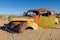 Red and yellow abandoned classic car in Namib desert near Solitaire, Namibia
