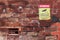 Red, yellow and black No Dumping, 24 Hours Video Surveillance, Violators Will Be Prosecuted warning sign on a brick wall