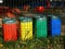 red, yellow blue and green plastic recycling bins in public park