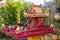 Red and yellow Buddhist sanctuary in tropical garden. Small buddhist temple in red and gold colors.