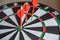 Red and yellow dart arrows hitting in the target center of dartboard. Success hitting target aim goal achievement concept
