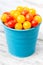 Red and yellow fresh cherry tomatoes in blue bucket