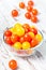 Red and yellow fresh cherry tomatoes in glass bowl
