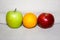 Red yellow, green apple and orange on a white background, as a traffic light