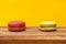 Red and yellow macarons in yellow pastel isolated background.