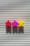 Red, yellow and purple figures of people on a striped background vertical photo, three figures of people of different colors in a