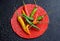 A red, yellow, red hot chili peppers on a black background and water droplets. Light focus