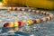 Red and yellow swimming safety buoys in a row for children`s protection in outdoor pool for deep end safety