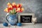 Red-yellow tulips in blue ceramic pitcher with Easter eggs and a