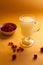 Redcurrants, glass cup with serum on a yellow background