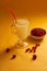 Redcurrants, glass cup with serum on a yellow background