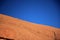 The reddish stone surface of Ayers Rock with two climbing ir.