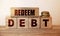 REDEEM debt words written on wooden cubes and stack of coins. Business concept