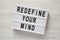 `Redefine your mind` words on lightbox over white wooden surface, top view. Overhead, flat lay