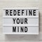 `Redefine your mind` words on modern board over white wooden background, top view. Overhead, flat lay