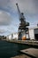 Redevelopment of seashore with refurbished gray historic crane and renovated storehouse on Queens Wharf, Wellington, New Zealand