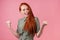 Redhair ginger woman amazed and surprised in cotton green white peas dress in pick background studio