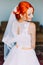 Redhair girl in a wedding dress, bright unusual appearance, elegant laced gown, studio interior