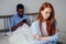 Redhaired ginger caucasian female and multi-ethnic afro man together lying in bed.