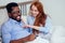 Redhaired ginger caucasian happy female and multi-ethnic afro man together lying in bed bedroom.lifestyle tolerance