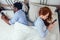Redhaired ginger caucasian happy female and multi-ethnic afro man together lying in bed bedroom looking at smartphones