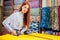 Redhaired ginger dressmaker woman cropping cutting textile in shop behind her background stock with bright sequins