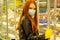 Redhaired ginger woman in casual black leather jacket buying products in empty super market second wave