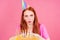 Redhaired ginger woman make a wish fingers crossed , eyes closed blowing out candles on a birthday cake