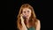 Redhaired girl talking on the phone. Black background