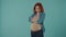 A redhaired pregnant woman strokes her bloated belly with a smile, gets angry, upset, offended. Woman in the studio on a