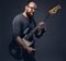 Redhead bearded male musician wearing glasses dressed in a gray t-shirt playing on electric guitar. Isolated on gray