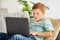 Redhead boy using laptop, playing online video game