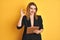 Redhead business caucasian woman holding clipboard over isolated background doing ok sign with fingers, excellent symbol