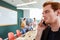 Redhead businessman talking on mobile phone while sitting in front of colleagues discussing at office
