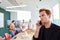 Redhead businessman talking on smart phone while sitting in front of colleagues discussing at office