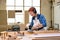 redhead caucasian woman carpenter drives circular saw, concentrated woman in factory
