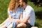 redhead couple with closed eyes embracing each other on grass