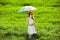 Redhead enchantress with umbrella and suitcase at spring country